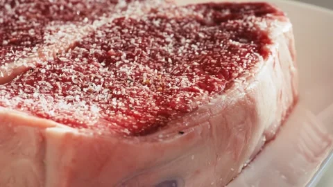 Cracking pepper onto a nice steak before cooking in slow motion Stock Footage 258306880