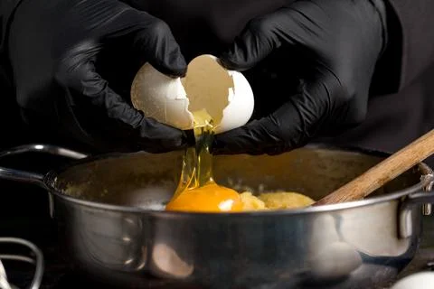 Cracking raw eggs into a bowl for making a cake Stockfoto's