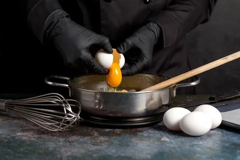 Cracking raw eggs into a bowl for making a cake Photos