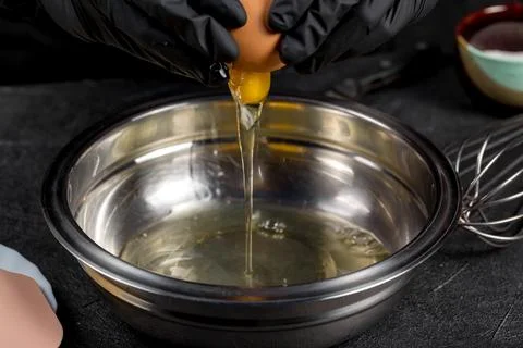 Cracking raw eggs into a bowl for making a cake 库存照片