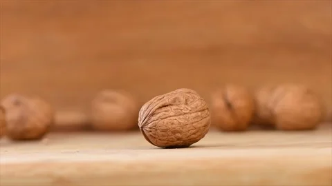 Cracking a walnut with hammer on wood background Stock Footage 141708011