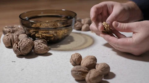 Cracking a walnuts at home. Hammer to break nuts. Collects a nuts in glass bowl Stock Footage 129085515