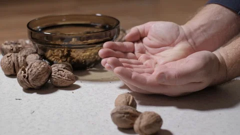 Cracking a walnuts at home. Hammer to break nuts. Collects a nuts in glass bowl Stock Footage 129085520