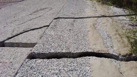 Cracks begin to form in both the pavement and the ground as a result of soil mov 스톡 동영상 344818484