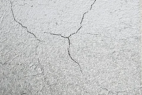 Cracks on the gray wall. Cement background. The concept of unfinished repairs. Stock Photos
