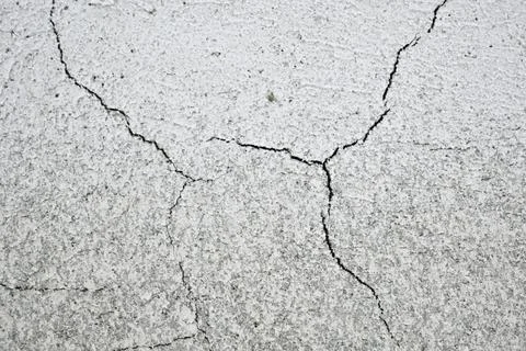 Cracks on the gray wall. Cement background. The concept of unfinished repairs. Stock Photos