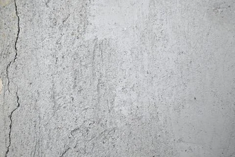 Cracks on the gray wall. Cement background. The concept of unfinished repairs. Stock Photos