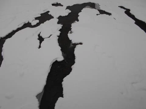 Cracks in the ice in the winter river in the mountains Stock Photos