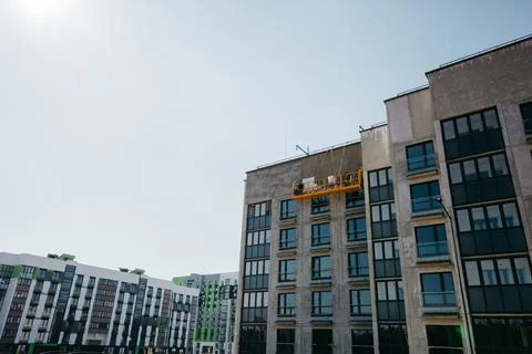 Cradle with builders at the construction site of multi-apartment modern houses Stock Photos
