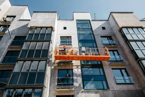 Cradle with builders at the construction site of multi-apartment modern houses Stock Photos