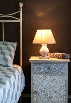Craft bedside lamp on a bedside table in bedroom. Stock Photos