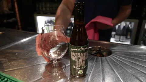 Craft Beer Bottle and Empty Glass on Stainless Steel Bar Counter Stock Footage 344105941