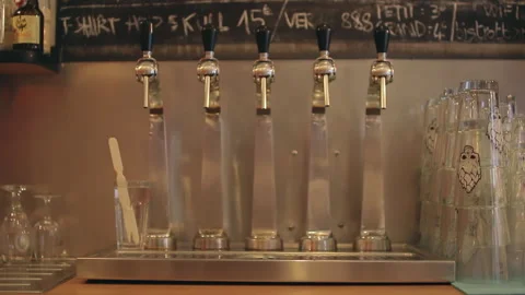Craft Beer Taps Rack Focus from Glass Stacks to Polished Metal Spigots Stock Footage 345961249
