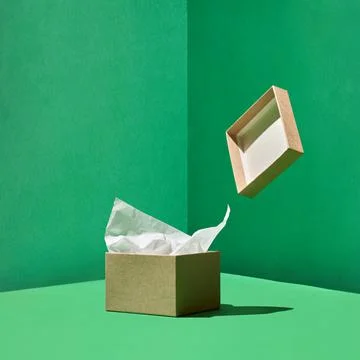 Craft box with wrapping paper inside and levitating box's cover on green back Stock Photos