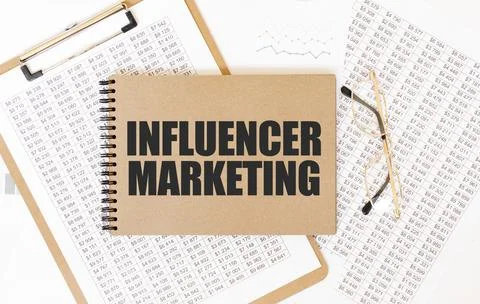 Craft colour notepad with text INFLUENCER MARKETING. Notepad with eyeglasse.. Stock Photos