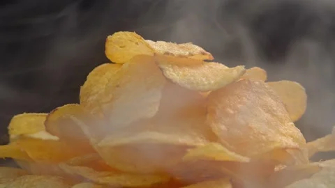 Craft crispy hot potato chips with smoke rotating on black background close up. Stock Footage 196697858