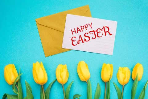 Craft envelope with an Easter card. Blue background with a frame of yellow tu Stock Photos
