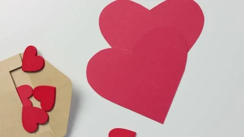 Craft envelope with many red hearts inside white table falling big paper heart Stock Footage 166535485
