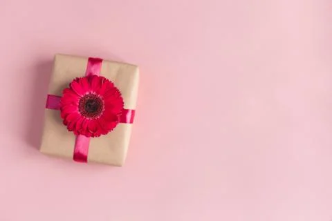 Craft gift box with pink flower and ribbon on a pastel pink background. Valen Stock Photos