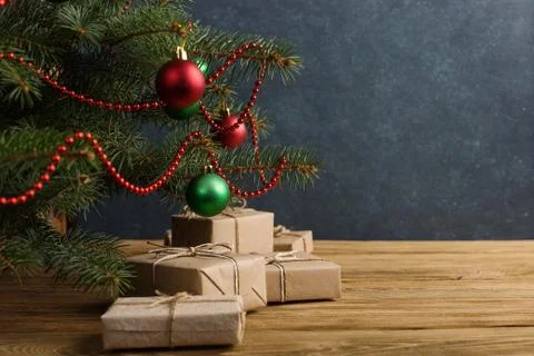 Craft gifts under the tree, on the table, against the wood background. The co Stock Photos