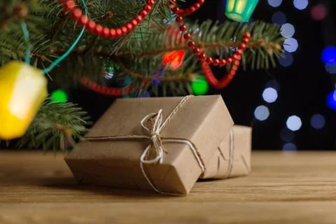 Craft gifts under the tree, on the table, against the background of blurry li Stock Photos