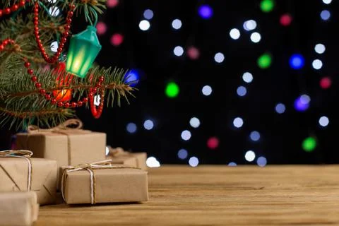 Craft gifts under the tree, on the table, against the background of blurry li Stock Photos