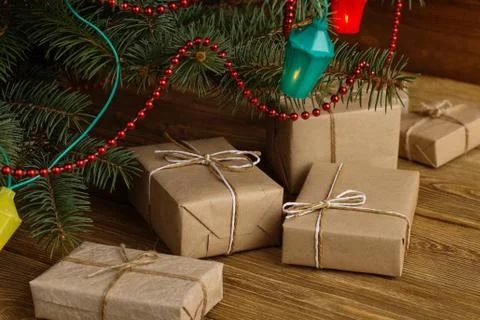 Craft gifts under the tree, on the table, against the wood background. The co Stock Photos