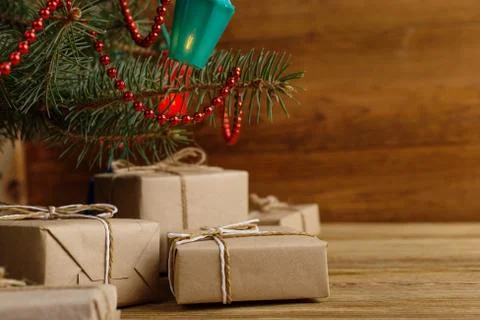 Craft gifts under the tree, on the table, against the wood background. The co Stock Photos