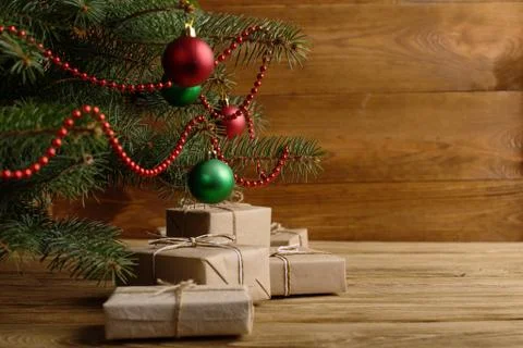 Craft gifts under the tree, on the table, against the wood background. The co Stock Photos