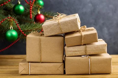 Craft gifts under the tree, on the table, against the wood background. The co Stock Photos