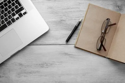 Craft notebook with pen, glasses, notebook on a light wooden background top view Stock Photos