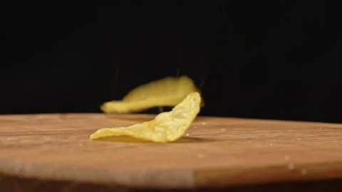 Craft Potato Chips Fall in Slow Motion on a Wooden Plate Stock Footage 260468844