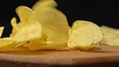 Craft Potato Chips Fall in Slow Motion on a Wooden Plate Stock Footage 260532258