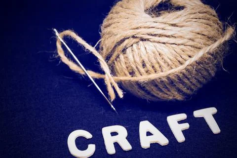 Craft a tangle of coarse brown threads with a large steel needle on a black back Stock Photos