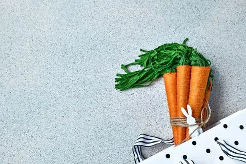 Craft wool thread carrots on gray background. Minimalist decor for Easter. .. Stock Photos