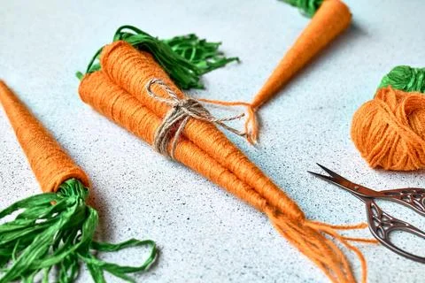 Craft wool thread carrots on gray background. Minimalist decor for Easter. .. Stock Photos