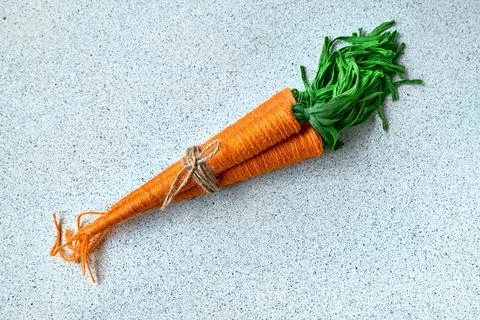 Craft wool thread carrots on gray background. Minimalist decor for Easter. .. Stock Photos