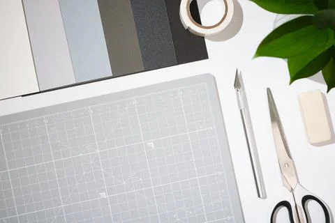 Craft workspace with cutting mat, utility knife, scissors, color samples and  Fotos de archivo