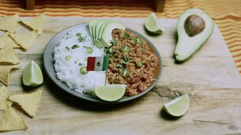 Crafted kitchen study of hand squeezing lime over rice and chili Stock Photos