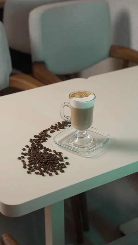 Crafted latte is presented on a table, accompanied by coffee beans 動画素材 315298901