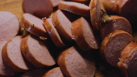 Crafted warm kitchen: slicing cooked sausage into rounds Stock Footage 342184470