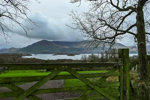 A crafted wooden gate frames a stunning view of a serene lake Stock Photos
