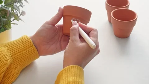 Crafting heart designs on clay pots with white marker in bright setting Stock Footage 306643237