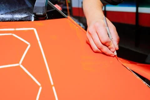 Crafting precision cuts on vibrant orange surface in workshop setting Stock Photos