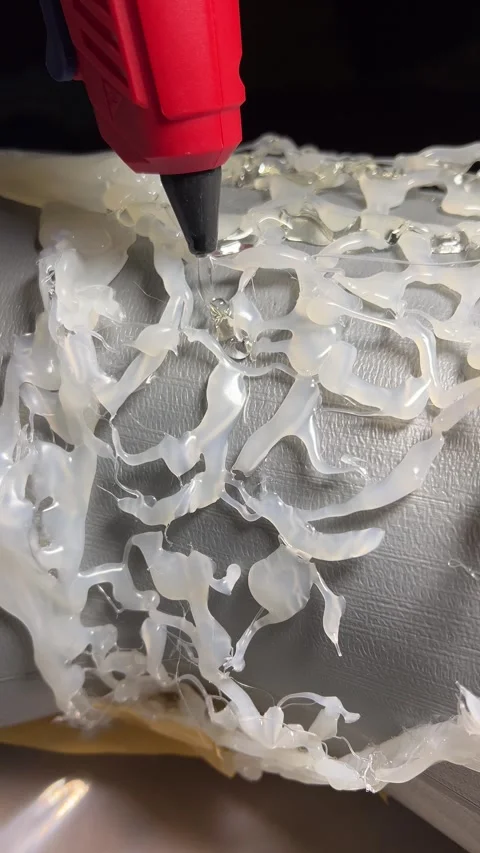 Crafting process. Transparent drop of hot thermo glue from red gun Stock Footage 306989524