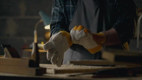Crafting table. Man Concentrated Puts gloves on his working hands In a carpe Stock Footage 251805654