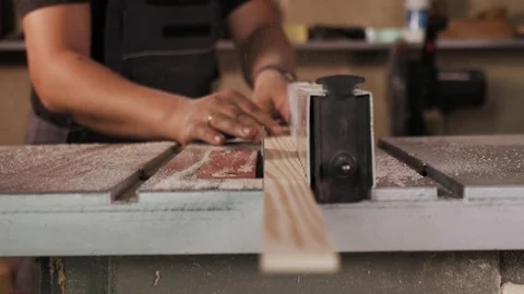 The craftman is working on electric saw machine. Sawing a large wooden board. Stockbeeldmateriaal 110348531