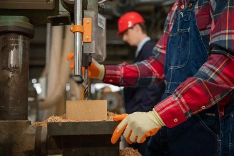 Craftman working on a wood solid inside of a factory with his boss beside him Stock Photos