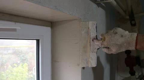 The craftsman aligns the window slope with plaster using a spatula. Stock Photos
