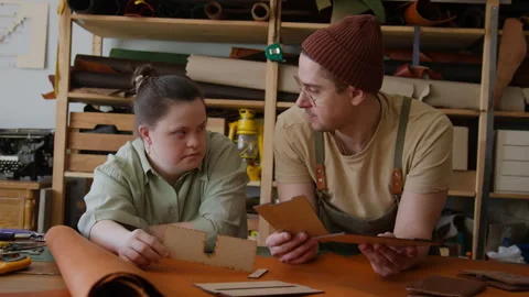 Craftsman and Apprentice with Disability Selecting Leather Material in Workshop Video stock 301677142